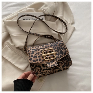 Détail du sac léopard avec boucle dorée posé sur un blazer beige élégant et moderne
