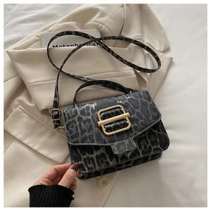 Détail du sac à main léopard avec boucle dorée et bandoulière sur un blazer beige