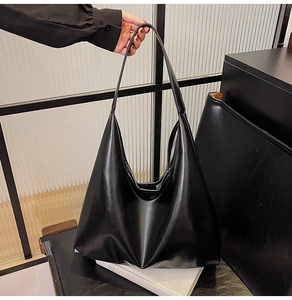 Detail of a large black glossy faux leather hobo tote bag with a minimalist design