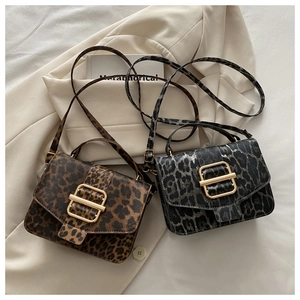 Détail de sacs bandoulière léopard avec boucles dorées sur un costume beige