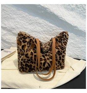 Detail of plush leopard print tote bag with brown leather strap on white blazer