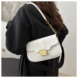 Detail of white crocodile pattern shoulder bag with gold metal buckle and chain strap