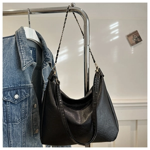 Détail d'un sac hobo en cuir noir souple avec bandoulière classique en chaîne argentée tressée