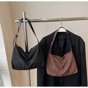 Detail view of retro suede hobo bags in black and brown with adjustable leather straps