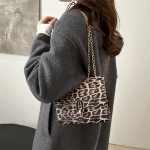 Stylish leopard print crossbody bag with gold chain strap and turn-lock on a model