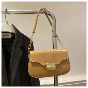 Detail of light tan faux crocodile texture on a chic shoulder bag with gold chain strap