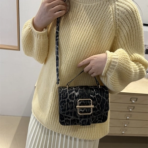 Sac bandoulière vintage à motif léopard avec boucle dorée porté à l'épaule d'un modèle
