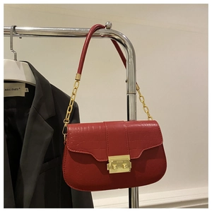 Detail of red crocodile pattern shoulder bag featuring a large gold rectangular twist lock