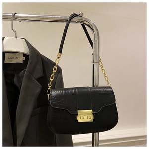 Detail of black crocodile texture bag with gold metal buckle and chain strap