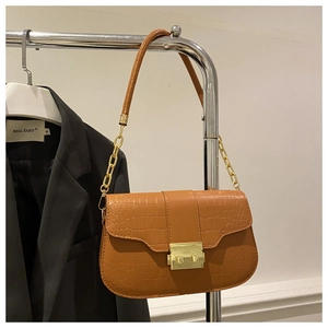 Detail of orange-brown crocodile pattern leather bag with gold rectangular metal buckle
