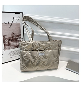 Detail of champagne gold quilted tote bag with fashion label and metallic gloss finish