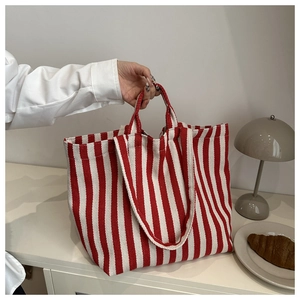 Détail d'un cabas en toile à rayures rouges et blanches avec doubles anses et texture