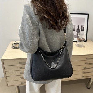 Grand sac fourre-tout en cuir noir avec chaîne argentée dans un décor minimaliste et chic