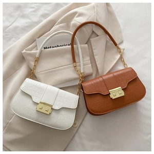 Detail of crocodile embossed leather texture on white and brown shoulder bags with gold buckles