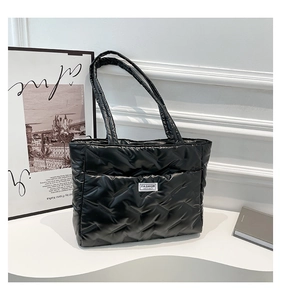 Close-up of quilted black puffer tote bag with glossy finish and fashion logo embroidery