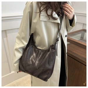 Detailansicht der dunkelbraunen Hobo-Tasche mit glänzender Faltenleder-Textur an der Schulter
