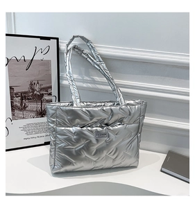Detail of silver metallic quilted tote bag with stitched grid pattern and fashion label