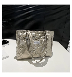 Detail of champagne gold quilted tote bag with metallic texture and Fashion label