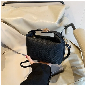 Close-up of black woven texture small crossbody bag with golden metal lock detail