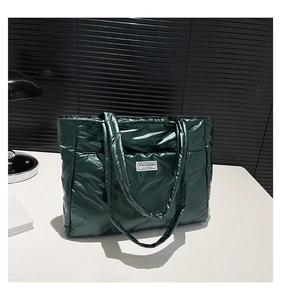 Detail of dark green quilted tote bag featuring Fashion Instinct label and glossy texture