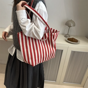 Sac fourre-tout en toile à rayures rouges et blanches porté par un mannequin en intérieur