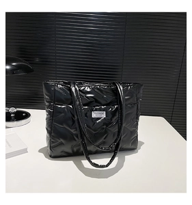 Detail of black quilted puffer tote bag featuring a Fashion Instinct rectangular logo label