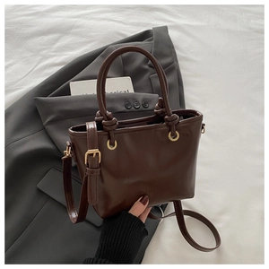 Detail of dark brown PU leather bucket bag with knotted handle and fashion embossing
