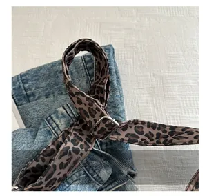 Détail de la bandoulière léopard en nylon avec boucle en métal sur sac en jean