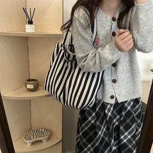 Grand sac cabas en toile rayé bleu et blanc porté avec une tenue décontractée chic