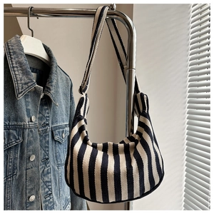 Detail of a large striped canvas hobo bag hanging on a rack with a denim jacket