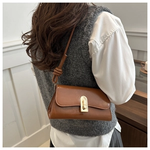 Detail of vintage brown leather baguette bag with gold twist lock and knotted strap