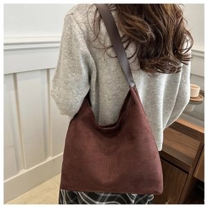 Model wearing a dark brown suede hobo tote bag in a cozy minimalist autumn setting