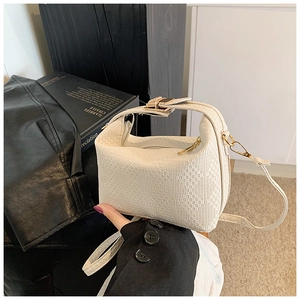 Close-up of cream white woven leather mini bag with gold buckle and adjustable strap