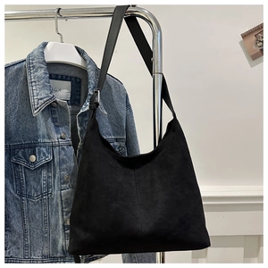 Close-up of black matte suede tote bag featuring vertical double stitching and metal buckle