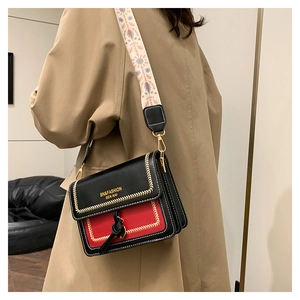 Detail view of contrast color crossbody bag with gold stitching and ethnic print strap