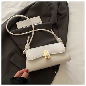 Detail of the white PU leather handbag with a golden rotating clasp on a grey blazer