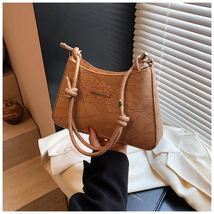 Detail of camel retro underarm bag with embossed lace texture and knot shoulder strap