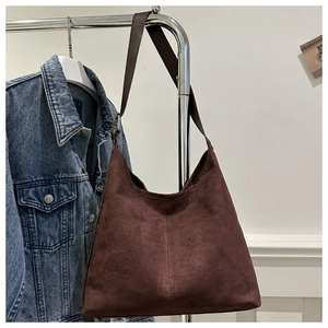 Close-up of brown suede tote bag featuring vertical stitching and a wide shoulder strap