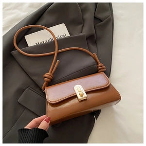 Macro detail of caramel brown faux leather bag featuring a glossy finish and gold metal lock