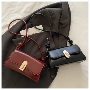 Detail of minimalist underarm bags in black and wine red with gold metal twist locks
