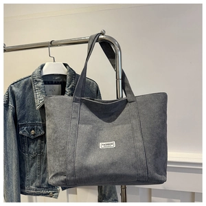 Detail of grey corduroy tote bag texture with Fashion Instinct label on denim background