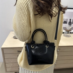 Chic black bucket bag with glossy finish and embossed Fashion text on minimalist design