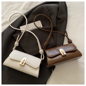 Detail view of cream and brown leather shoulder bags with gold metal clasps and knot straps