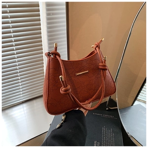 Detail of brown embossed leather handbag with twisted handle and gold hardware