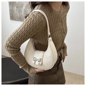Detailed view of cream white pleated hobo bag with a decorative silver metal bow accent
