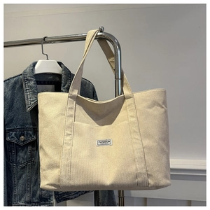 Detailed macro view of the beige corduroy fabric texture and the fashion label on the tote bag