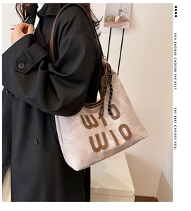 Detail of grey canvas tote bag with brown leather letters and a tennis racket charm
