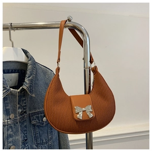 Close-up of pleated brown leather hobo bag with a decorative silver bow buckle detail