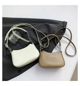 Detail of minimalist leather crescent bags with silver chain straps and logo text