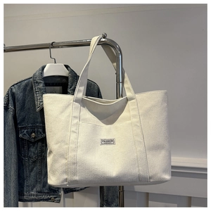 Close-up of off-white corduroy tote bag featuring a black Fashion Instinct label patch